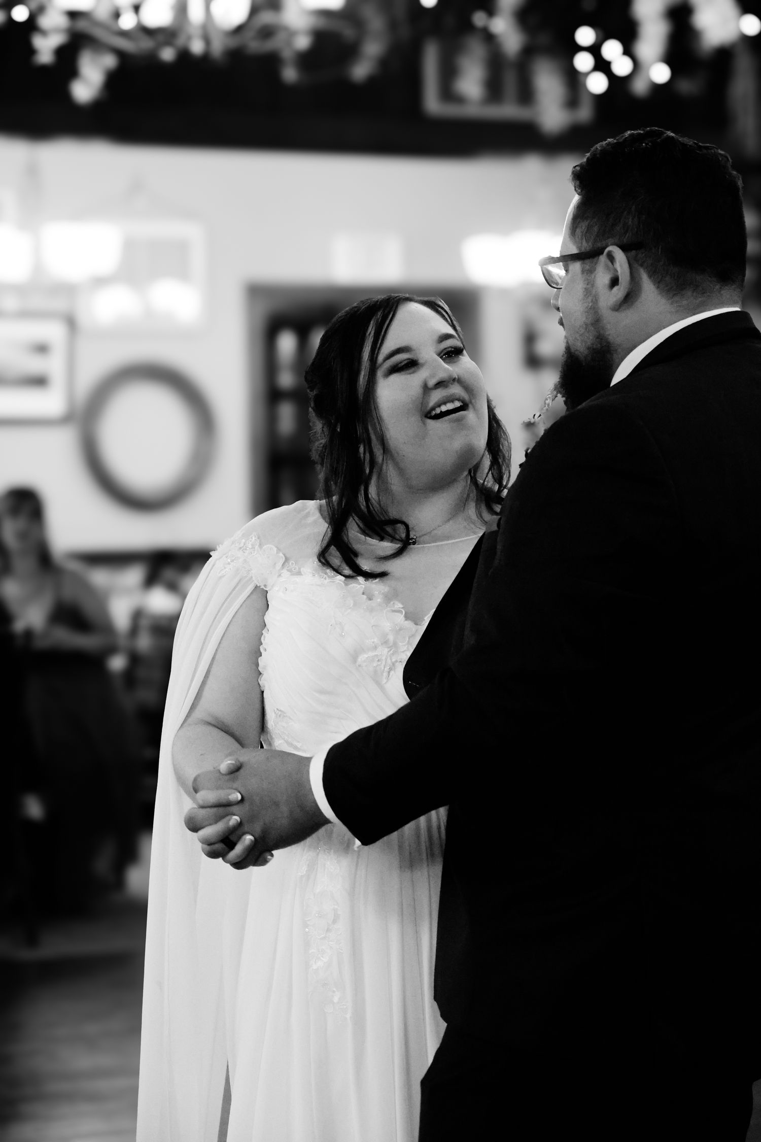 Black and white photo series showing a couple dancing at a wedding reception, with the bride in white dress twirling.