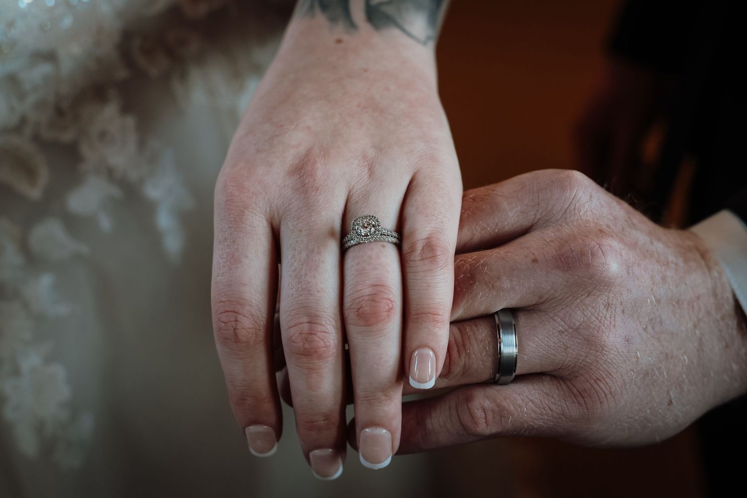 Close-up of newlyweds hands showing diamond engagement ring and wedding band after exchanging vows.