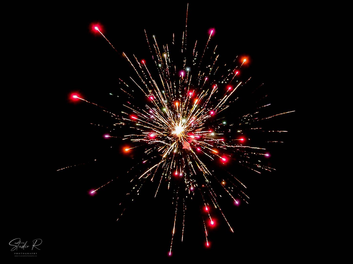 Red and gold fireworks burst against a dark night sky in a stunning display of light and color.