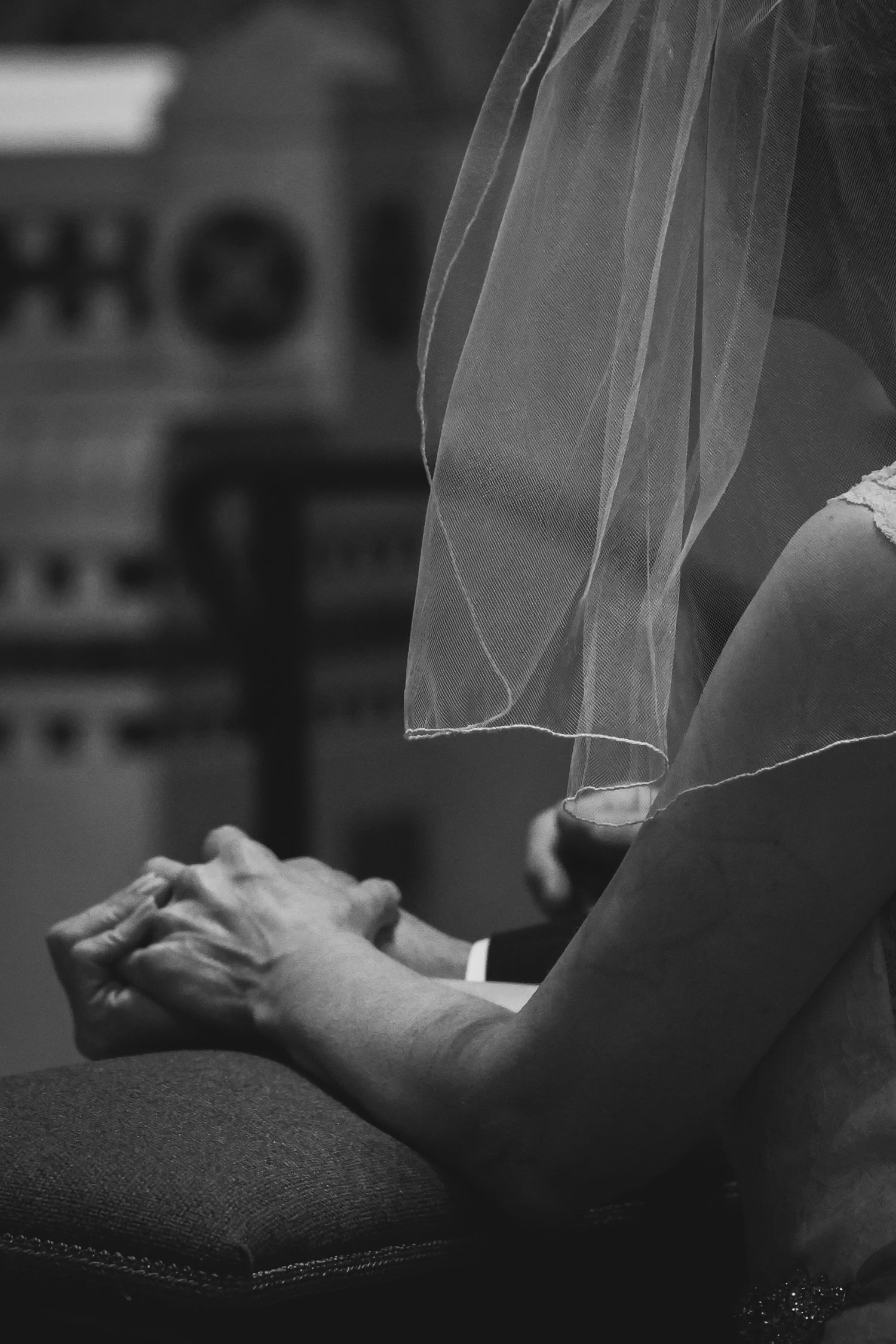 Black and white close-up of hands holding a delicate veil or sheer fabric in an artistic composition.