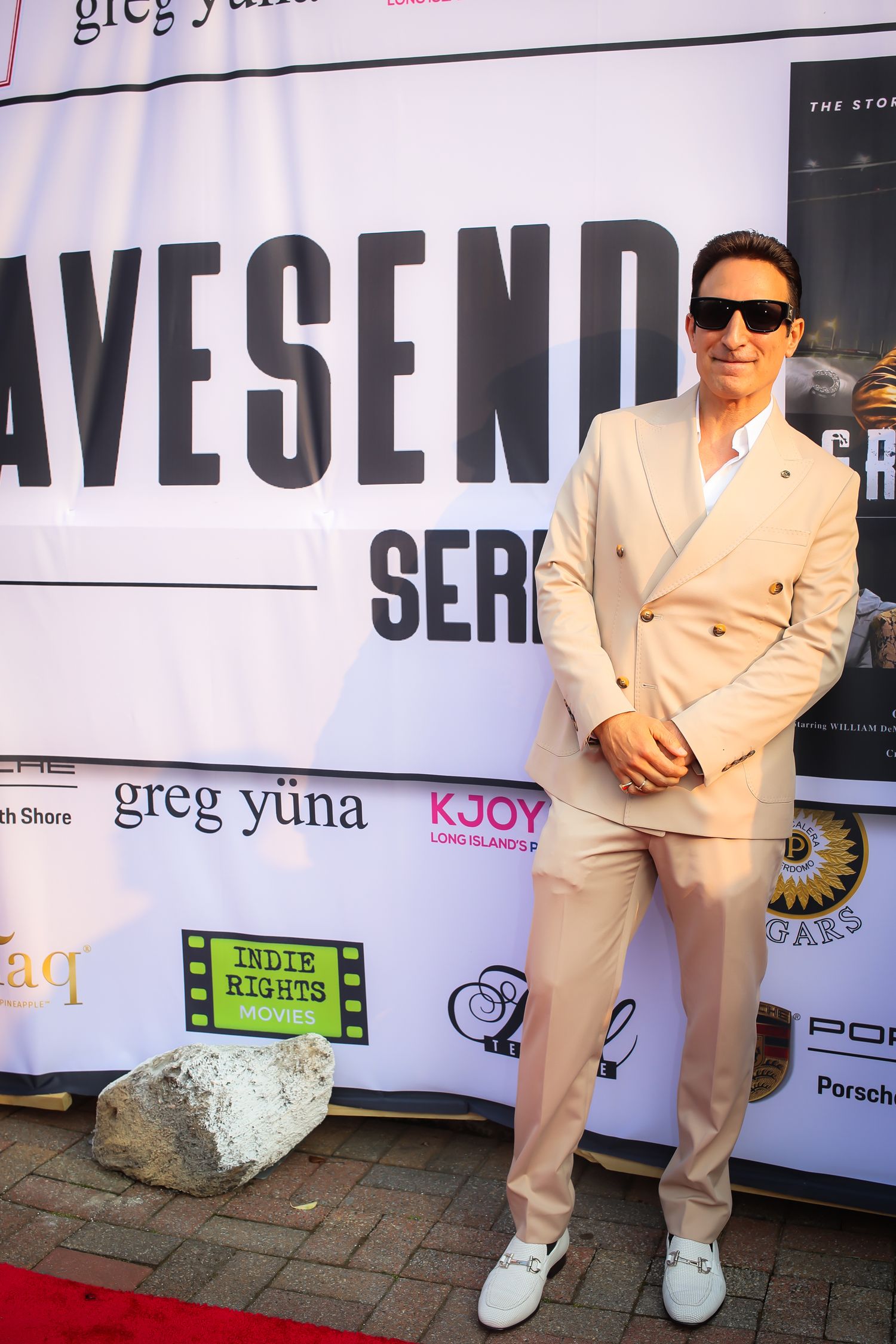 A collage of four photos showing someone in a white suit and sunglasses posing against a branded backdrop.