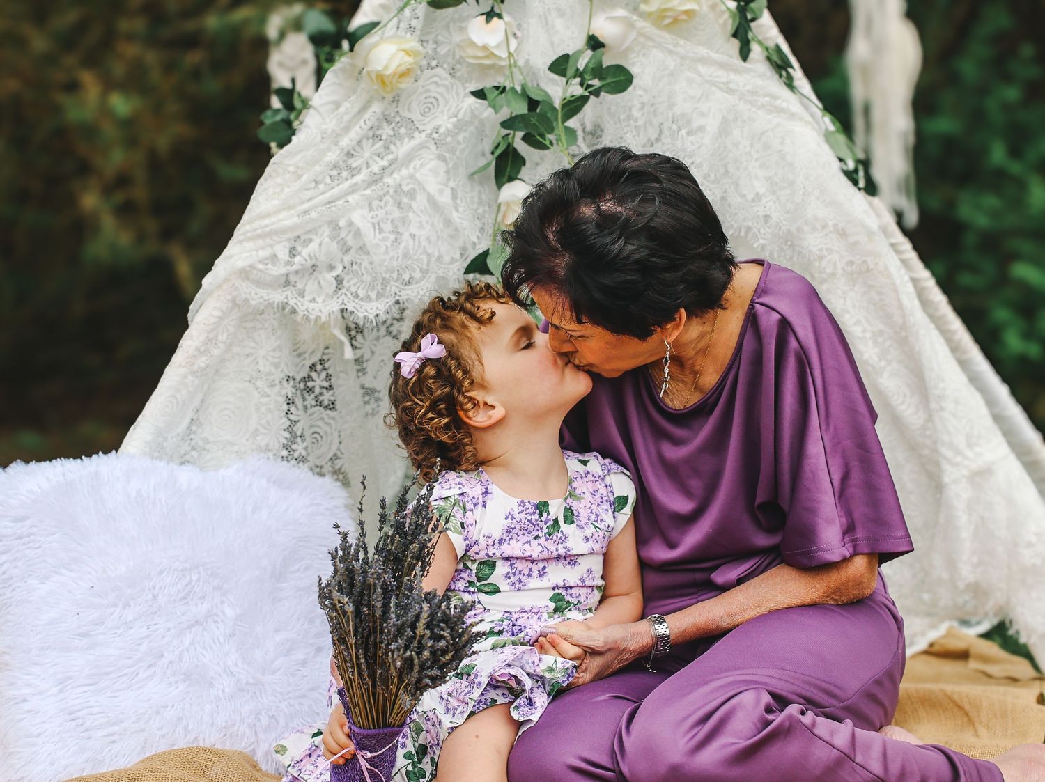 A tender moment shared between two people in a floral wedding setting with a white lace backdrop and lavender decor.