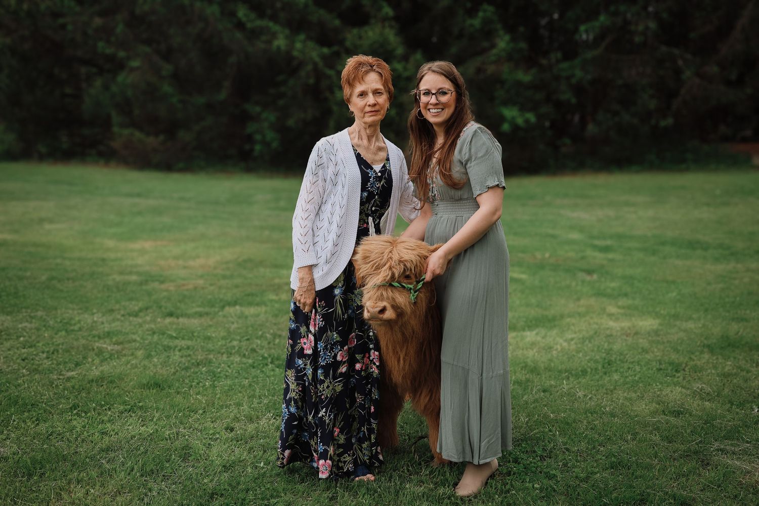 Two people stand close together on a grassy lawn during an outdoor photo session.