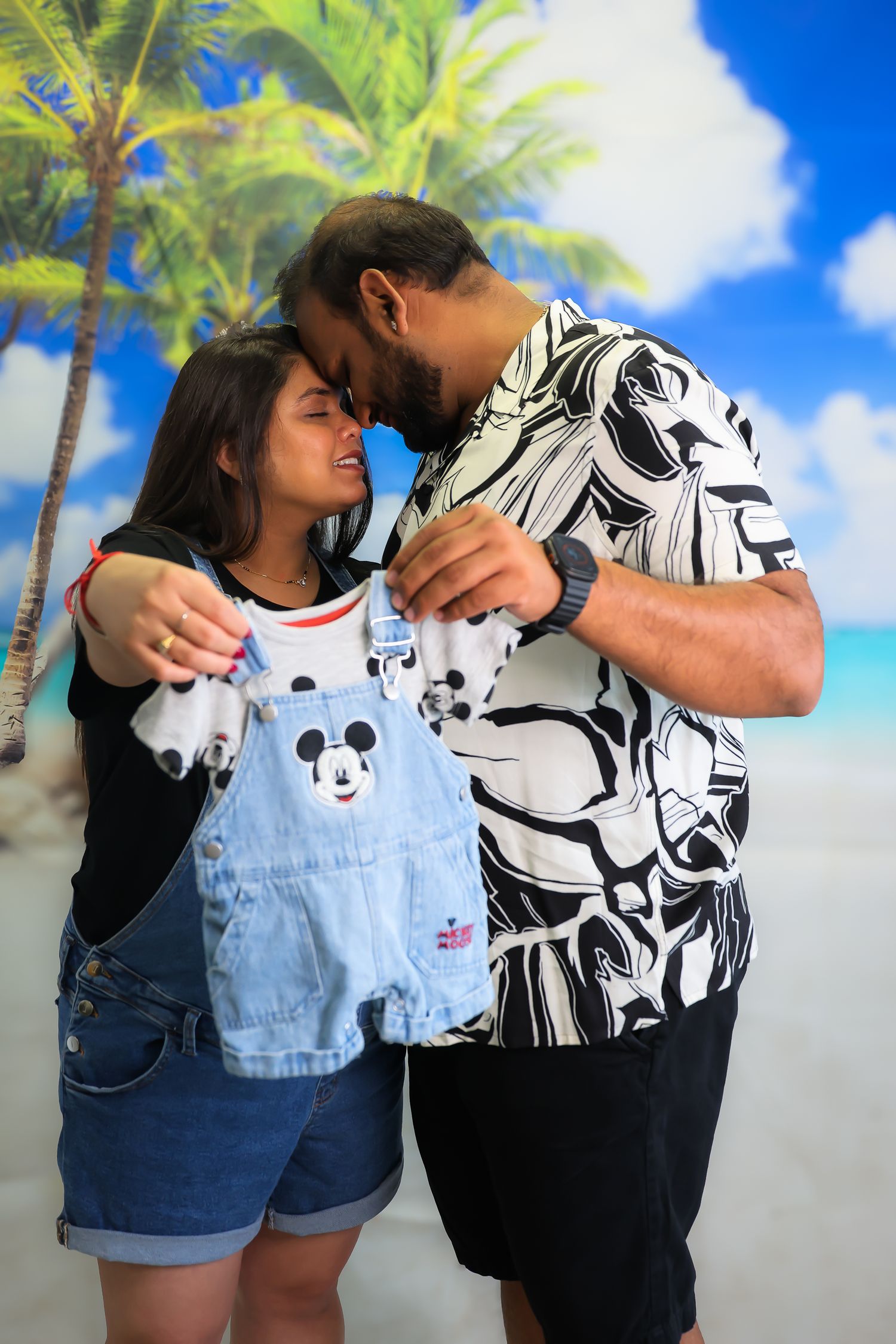 A couple in casual attire embracing against a blue sky and palm tree background in a series of romantic photos.