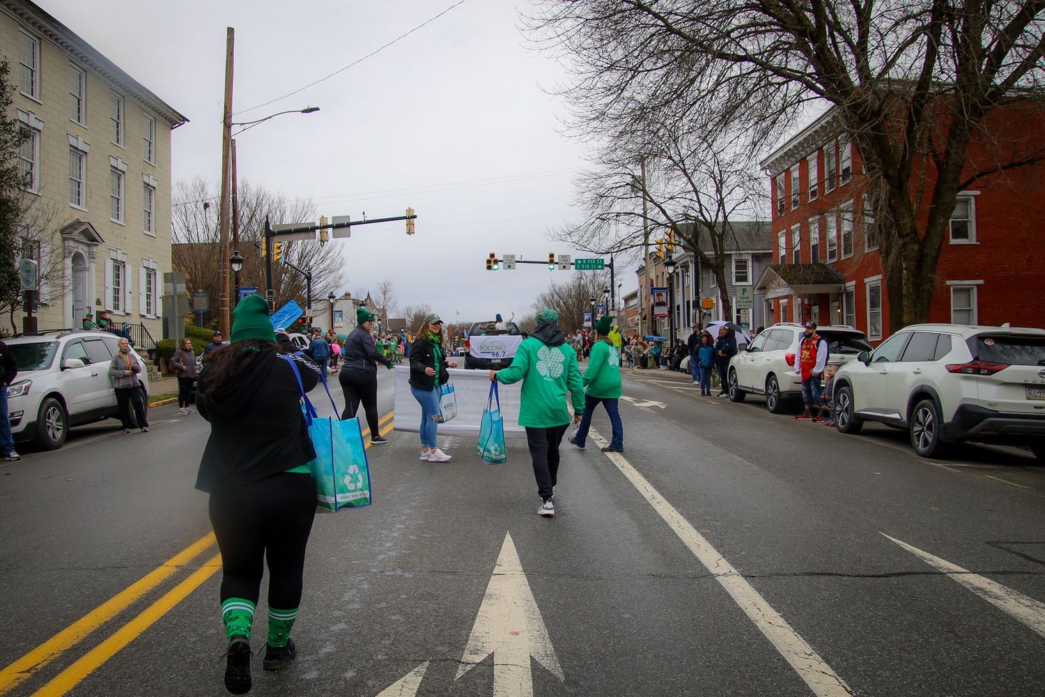 A sequence of street scenes showing people in bright green and teal costumes walking along a city sidewalk in winter.
