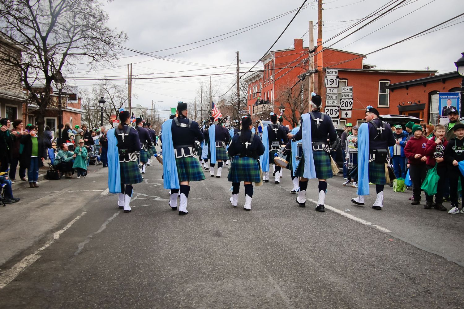 A group of performers in traditional blue and white costumes line up along a street during a cultural parade.