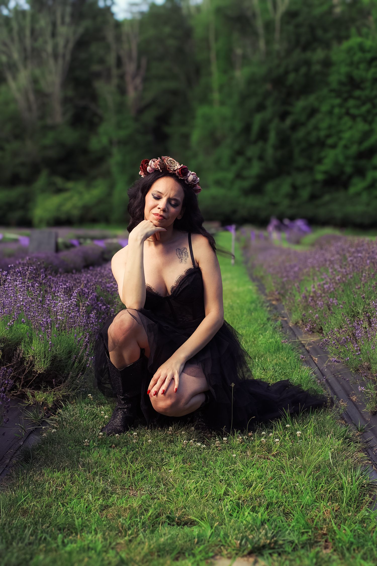 A figure in a black dress poses gracefully among blooming purple lavender fields on a summer day.