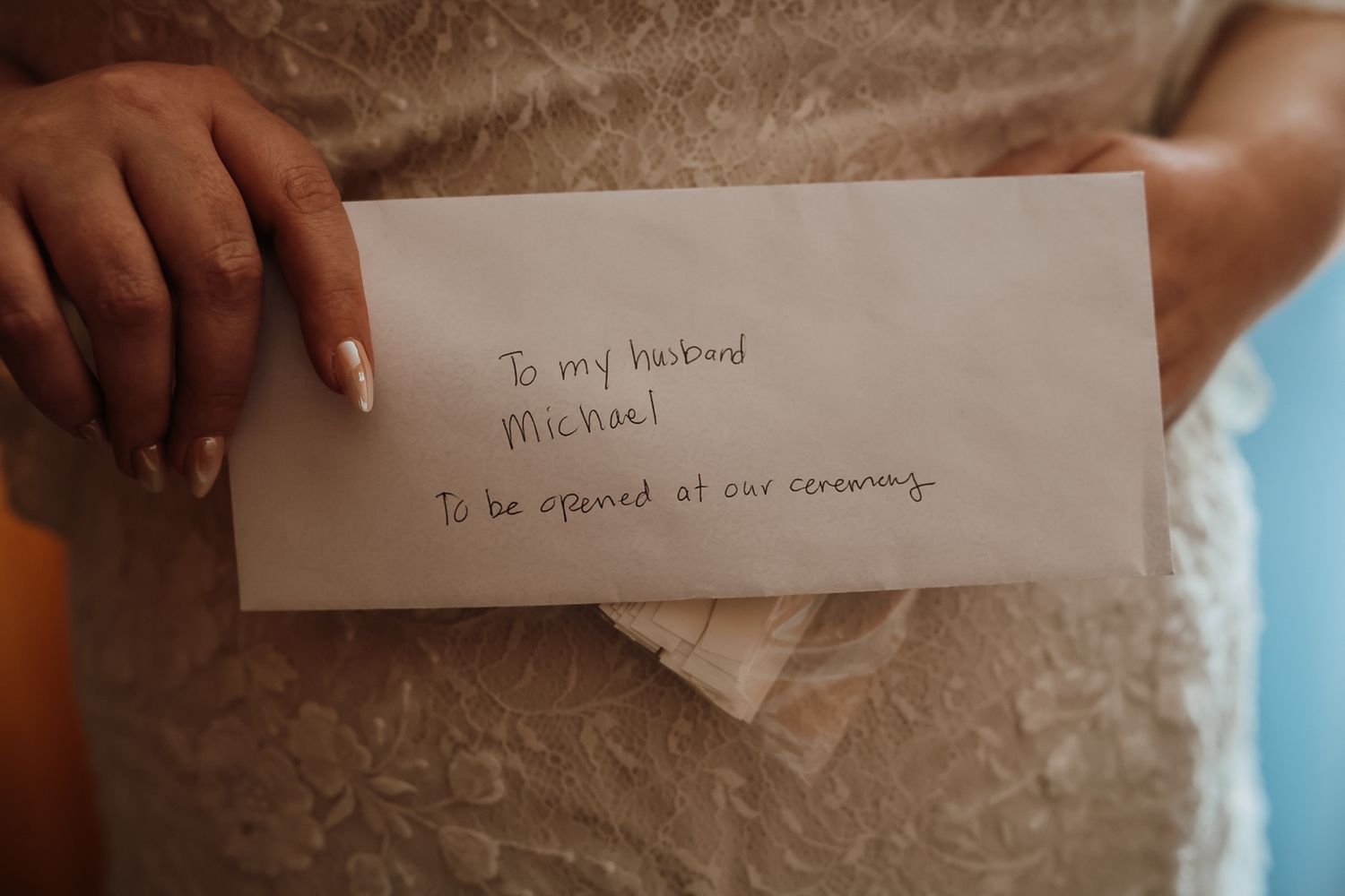 Bride holding a handwritten envelope addressed to her husband Michael, to be opened at their wedding ceremony.