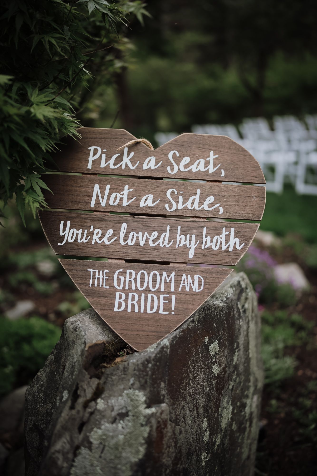 Heart-shaped wooden wedding sign reading Pick a Seat Not a Side You're Loved by Both the Groom and Bride.