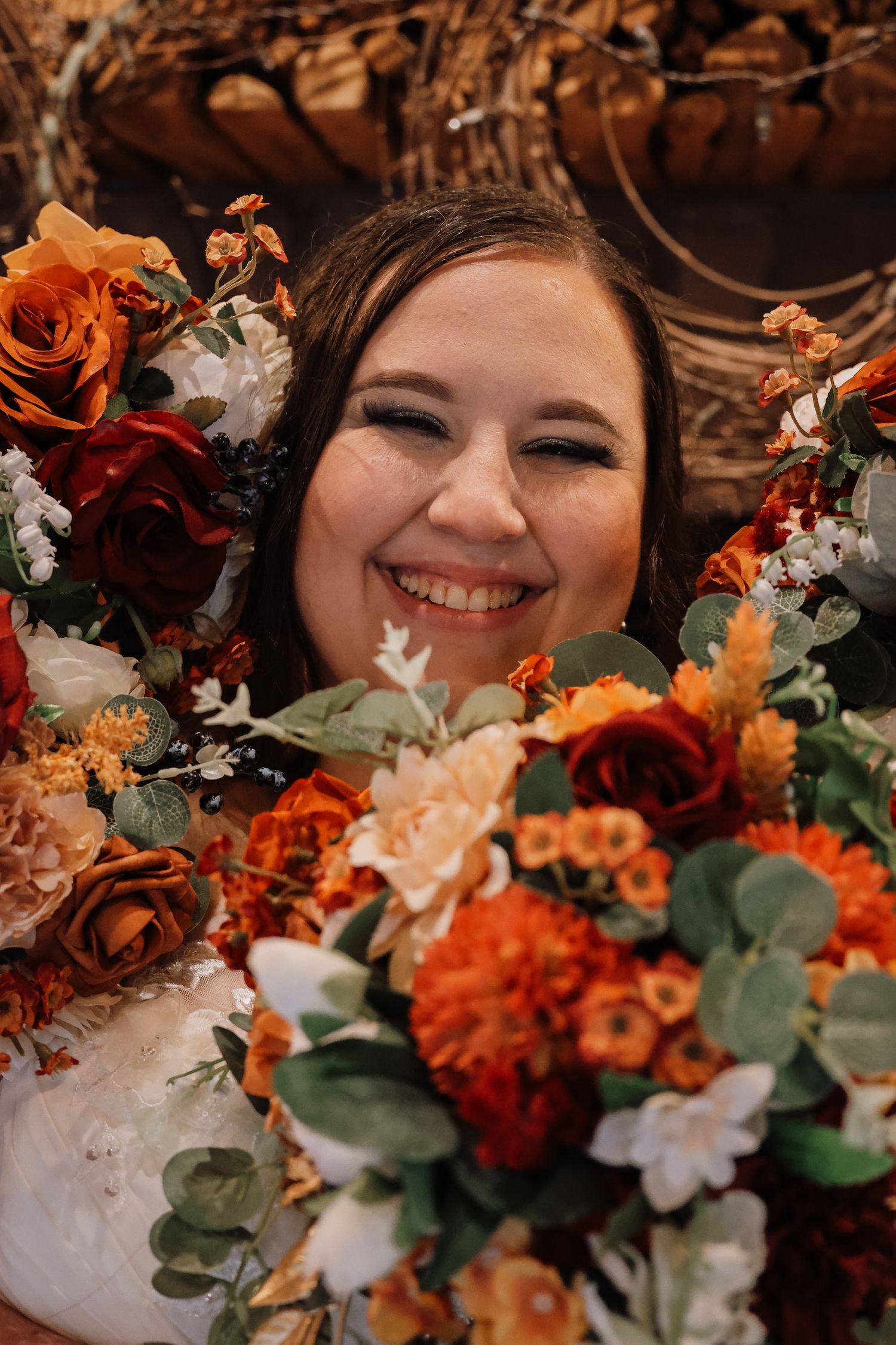A romantic fall wedding table setting with orange and white flowers and lush greenery arrangements.