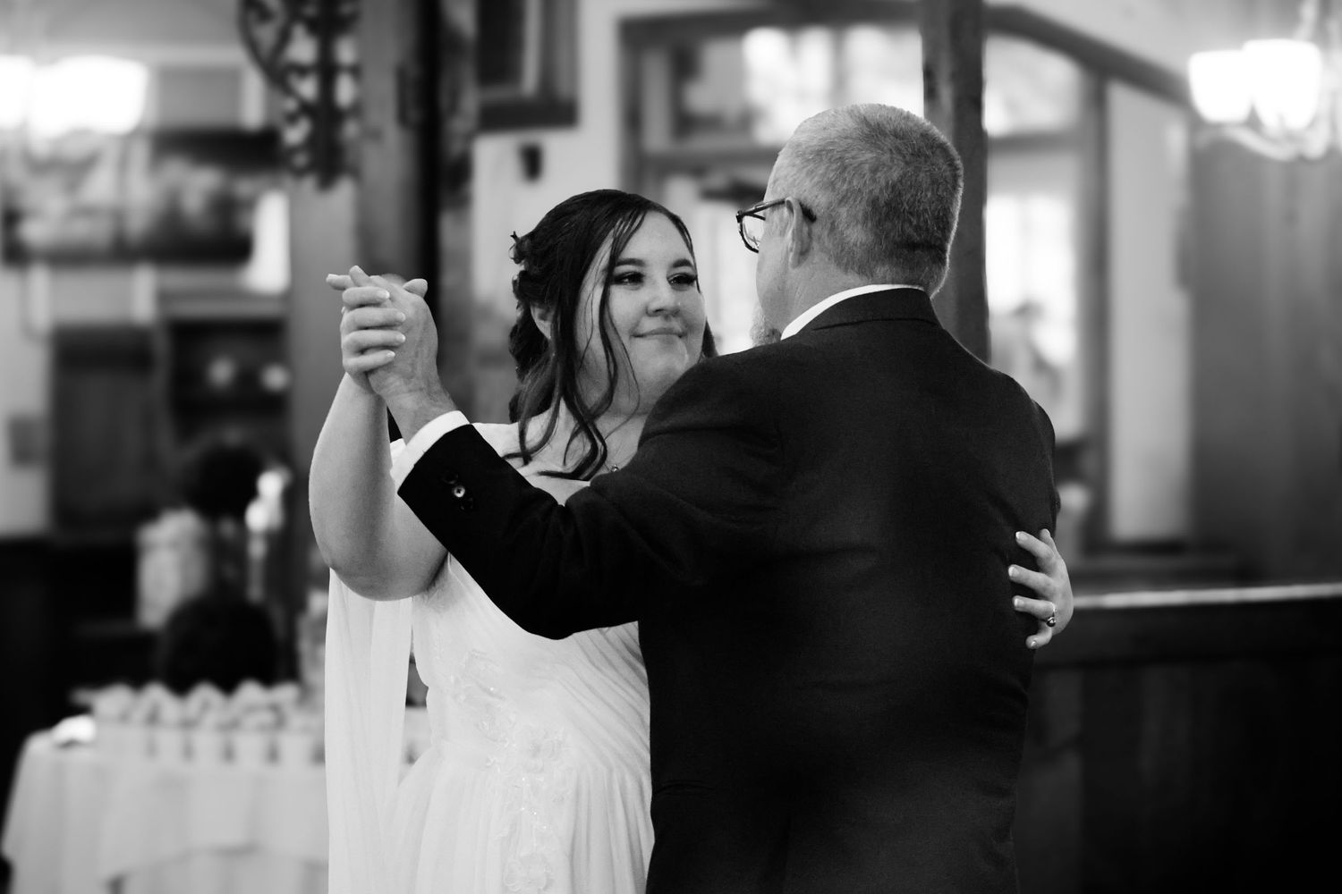 A couple dances together at an elegant wedding reception in black and white.