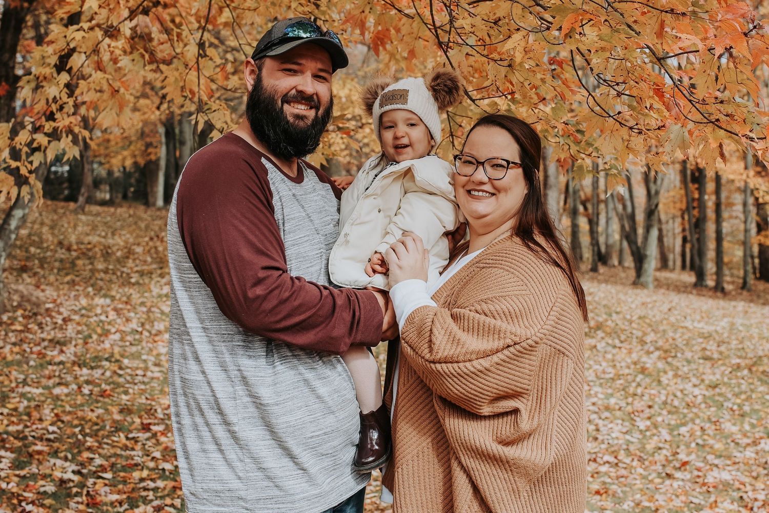 A couple shares tender moments together during an autumn photoshoot with orange fall foliage in the background.