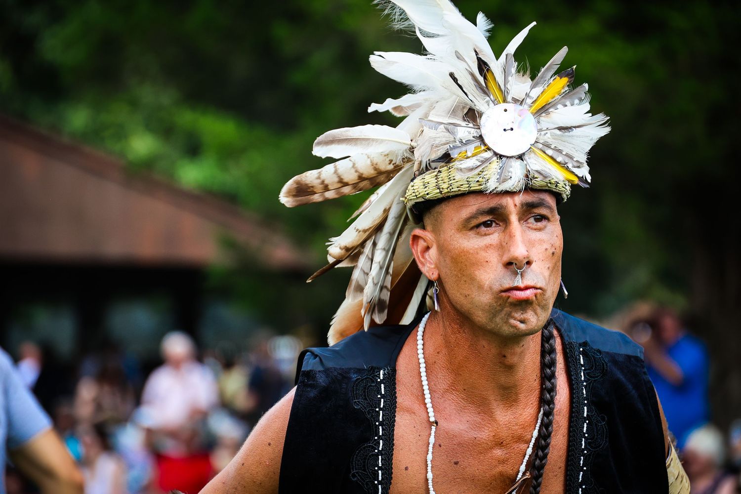 Traditional dancers in white feather headdresses perform at an outdoor cultural festival in Hawaii.