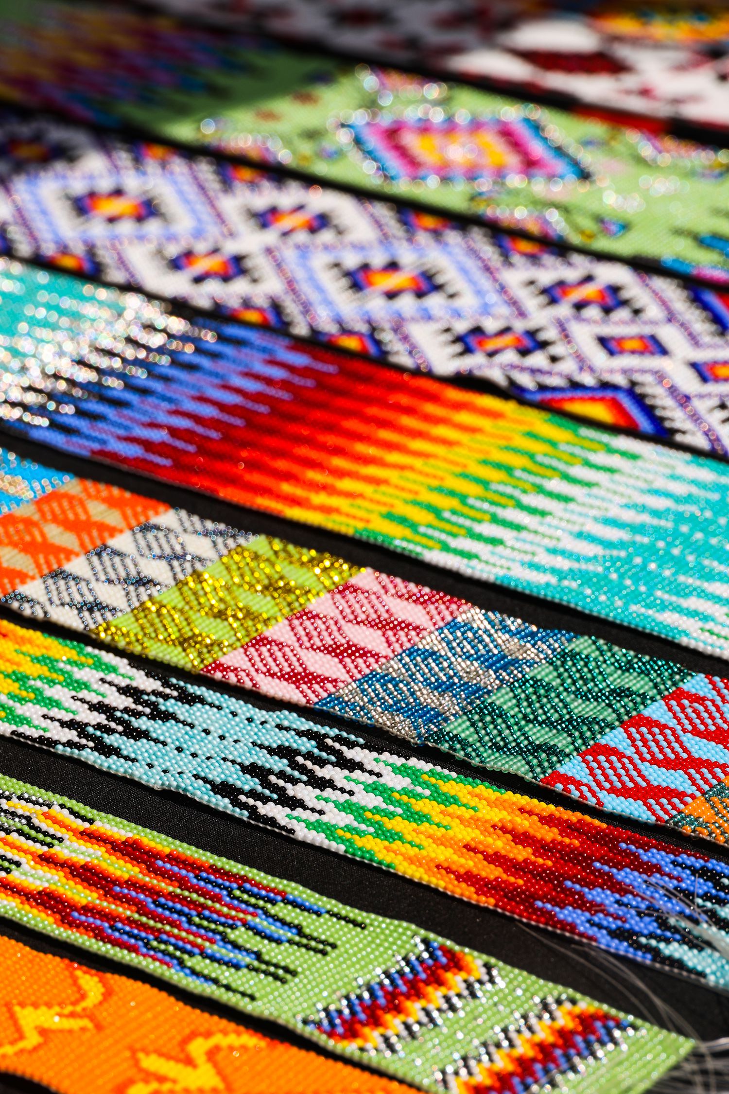 Close-up view of colorful woven friendship bracelets with intricate geometric patterns laid out in a row.