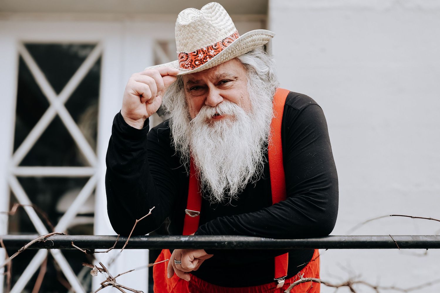 A person in a black shirt and red suspenders sits at a table outdoors.
