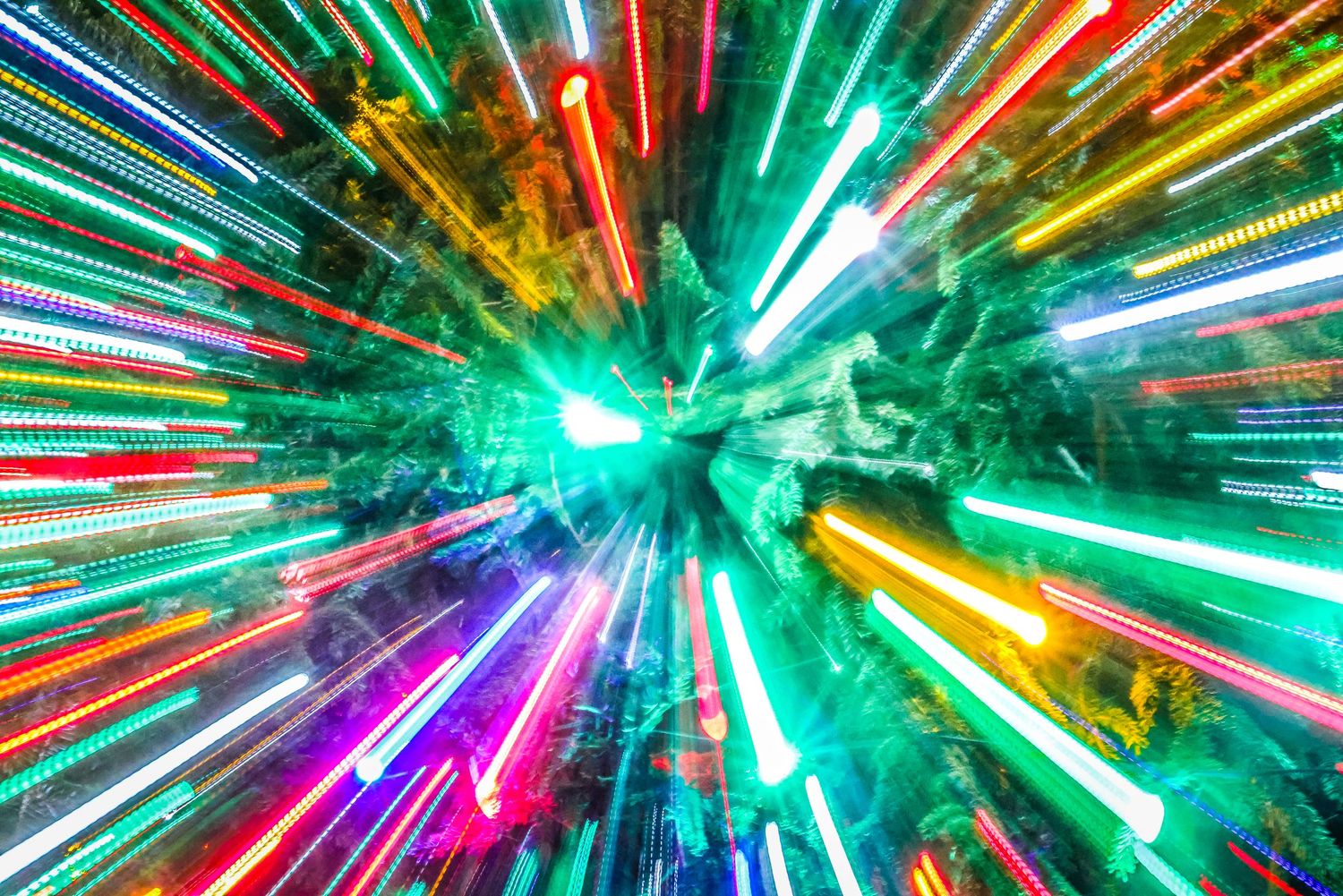 Abstract zoom effect photograph showing vibrant neon lights radiating outward in green, pink, and yellow streaks.