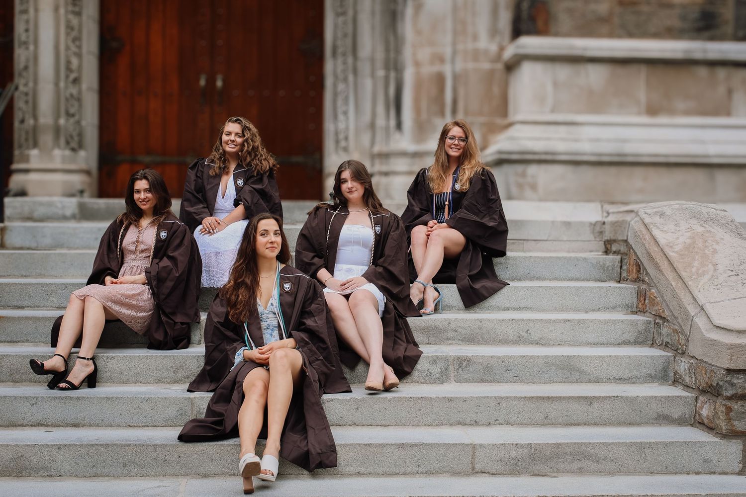 A group sits on stone steps wearing casual attire and dark jackets in an urban setting.