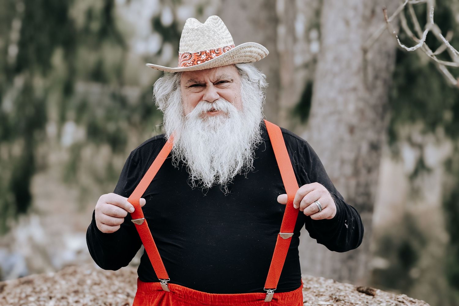 A person wearing a black shirt and red suspenders stands in a snowy forest setting.