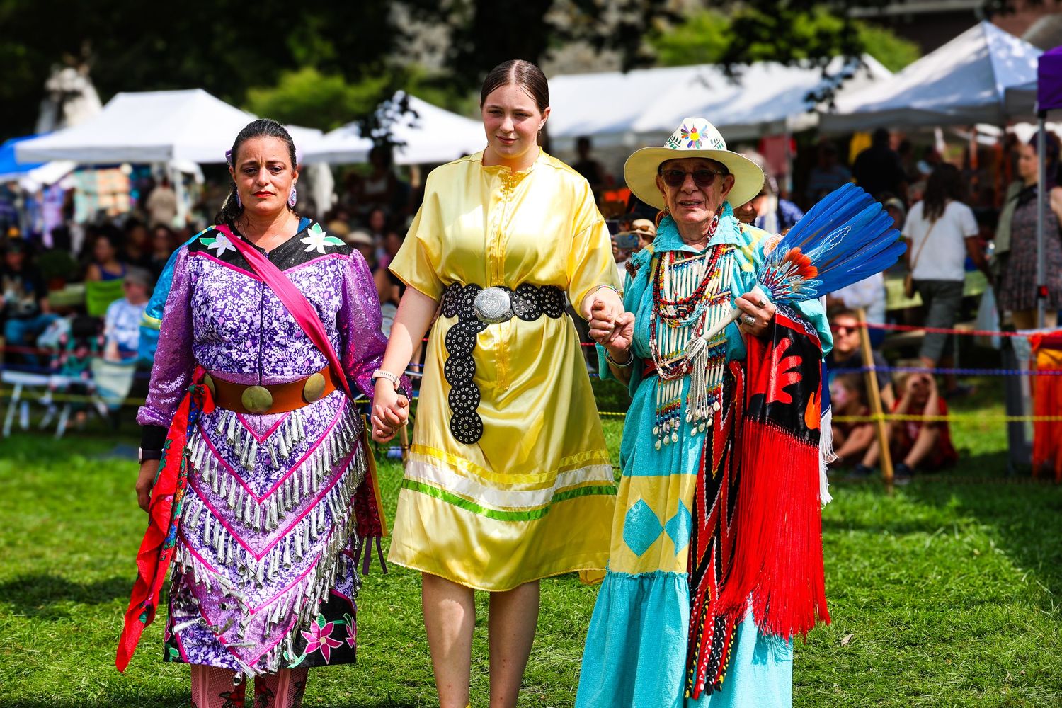 Dancers in colorful regalia perform traditional movements at an outdoor Native American powwow celebration.