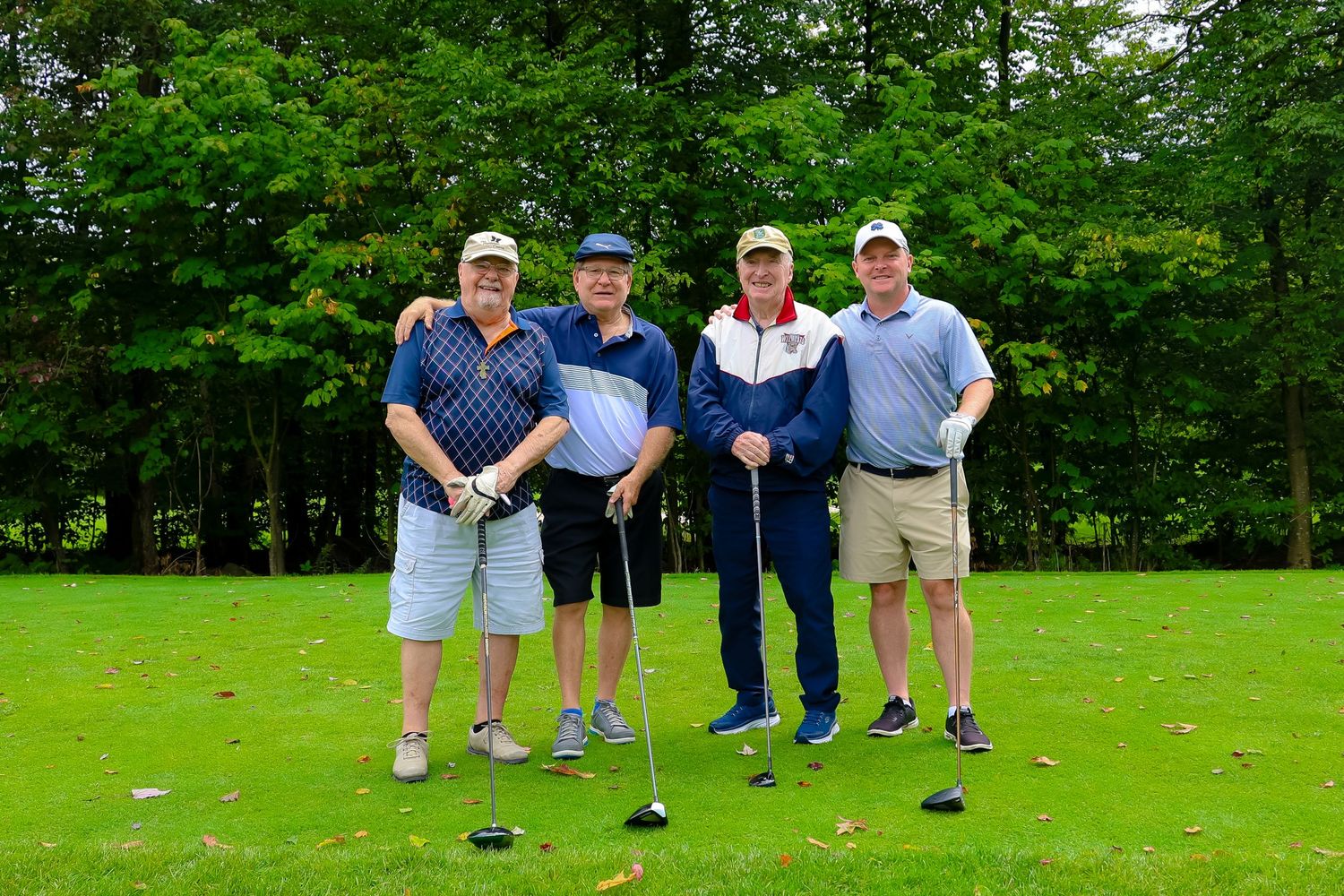 A group of golfers stand together on a lush green course preparing to tee off.