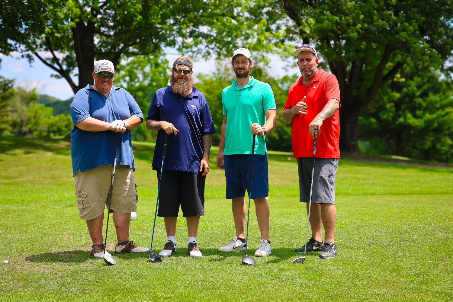 Group of golfers standing together on a lush green course during a sunny summer day.