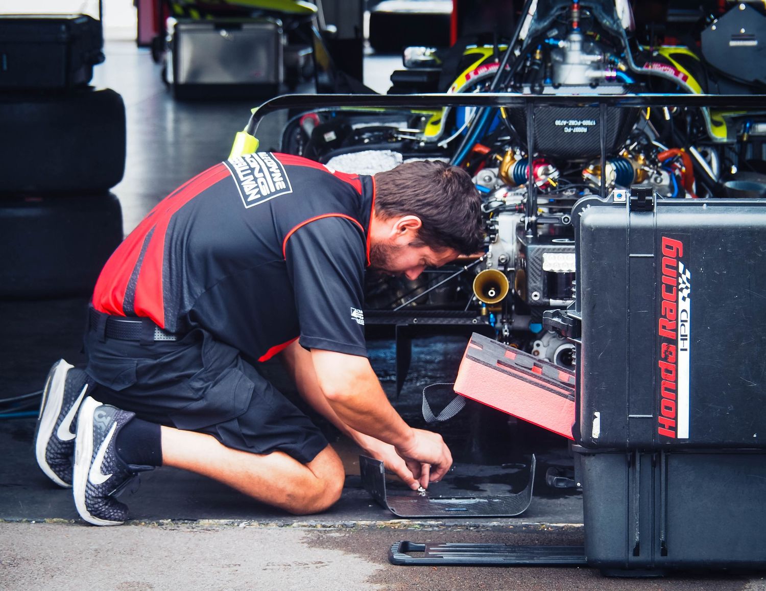 Auto racing pit crew member performs maintenance on a race car during a pit stop.