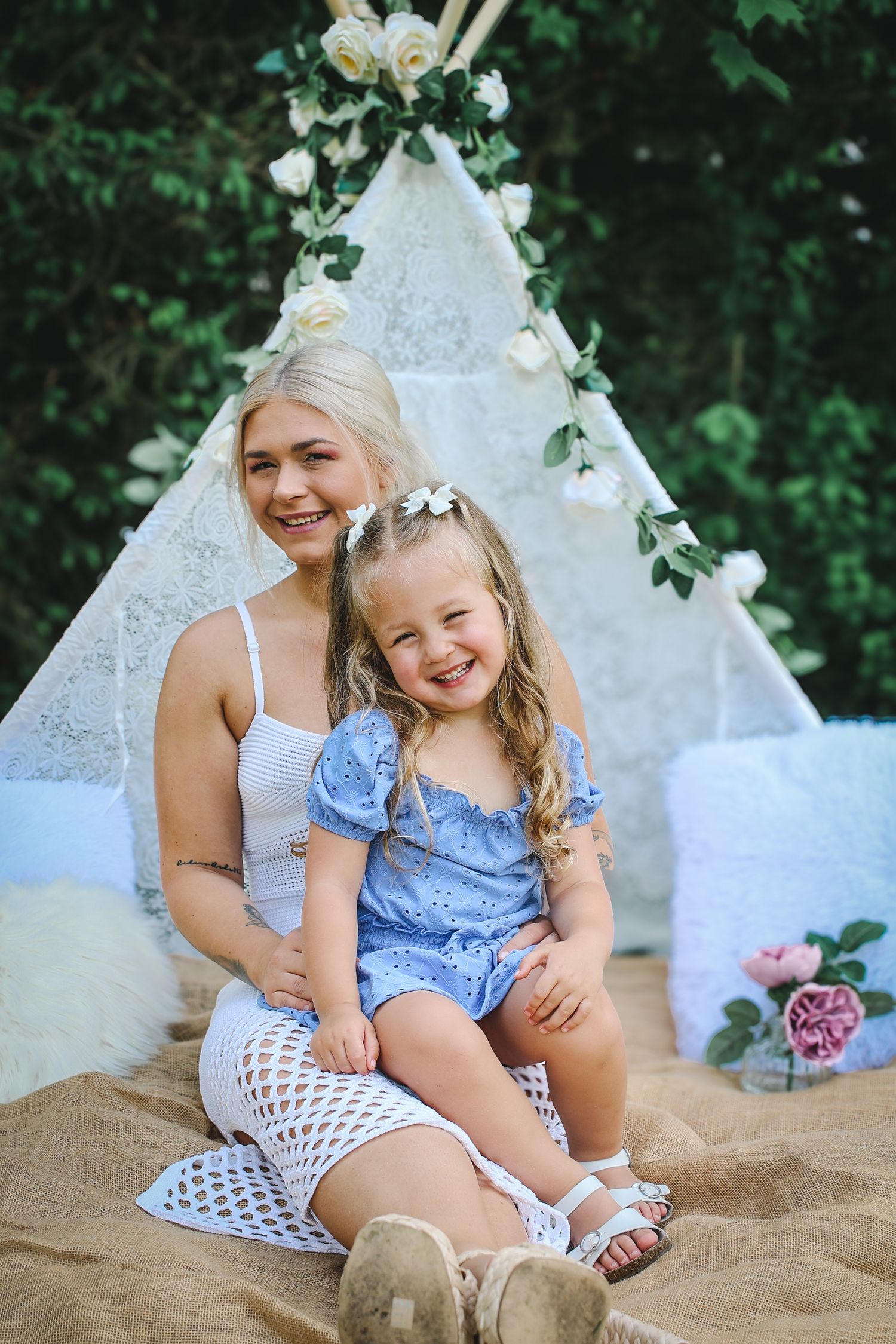 A decorative white lace teepee with floral accents creates a whimsical backdrop for a sweet summer photoshoot.