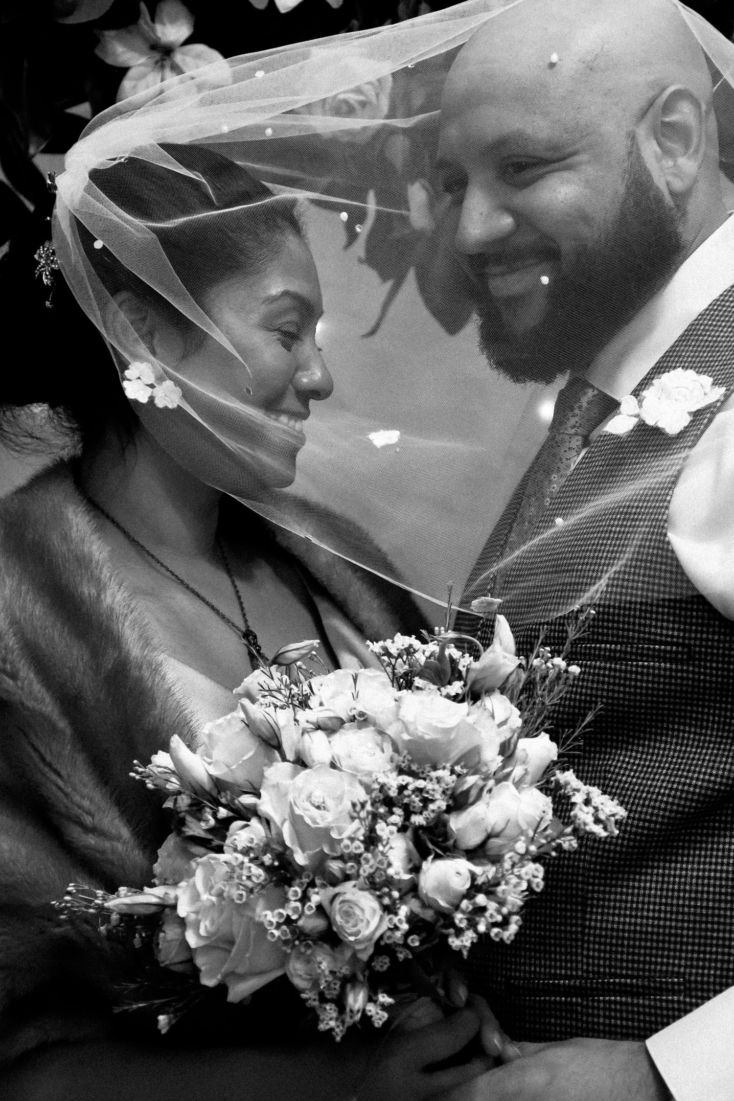A romantic black and white wedding photo series showing close-up moments between newlyweds with a white floral bouquet.