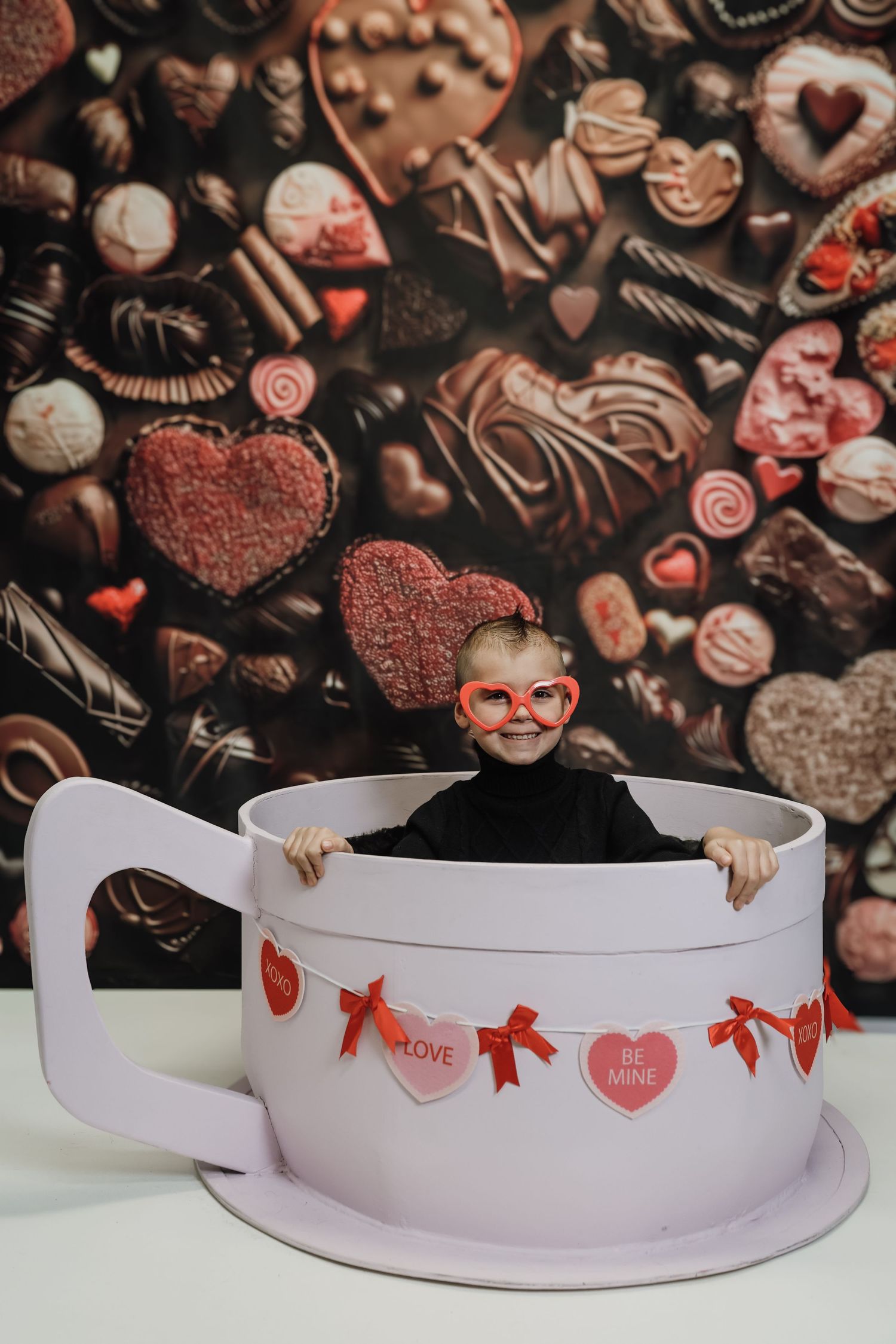 A sequence of four photos showing a paper banner with heart decorations gradually being revealed against a chocolate background.