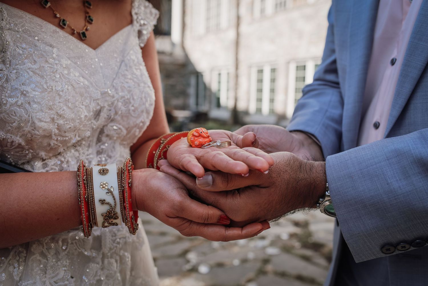 Close-up of hands holding red rose petals during an intimate wedding ceremony moment.