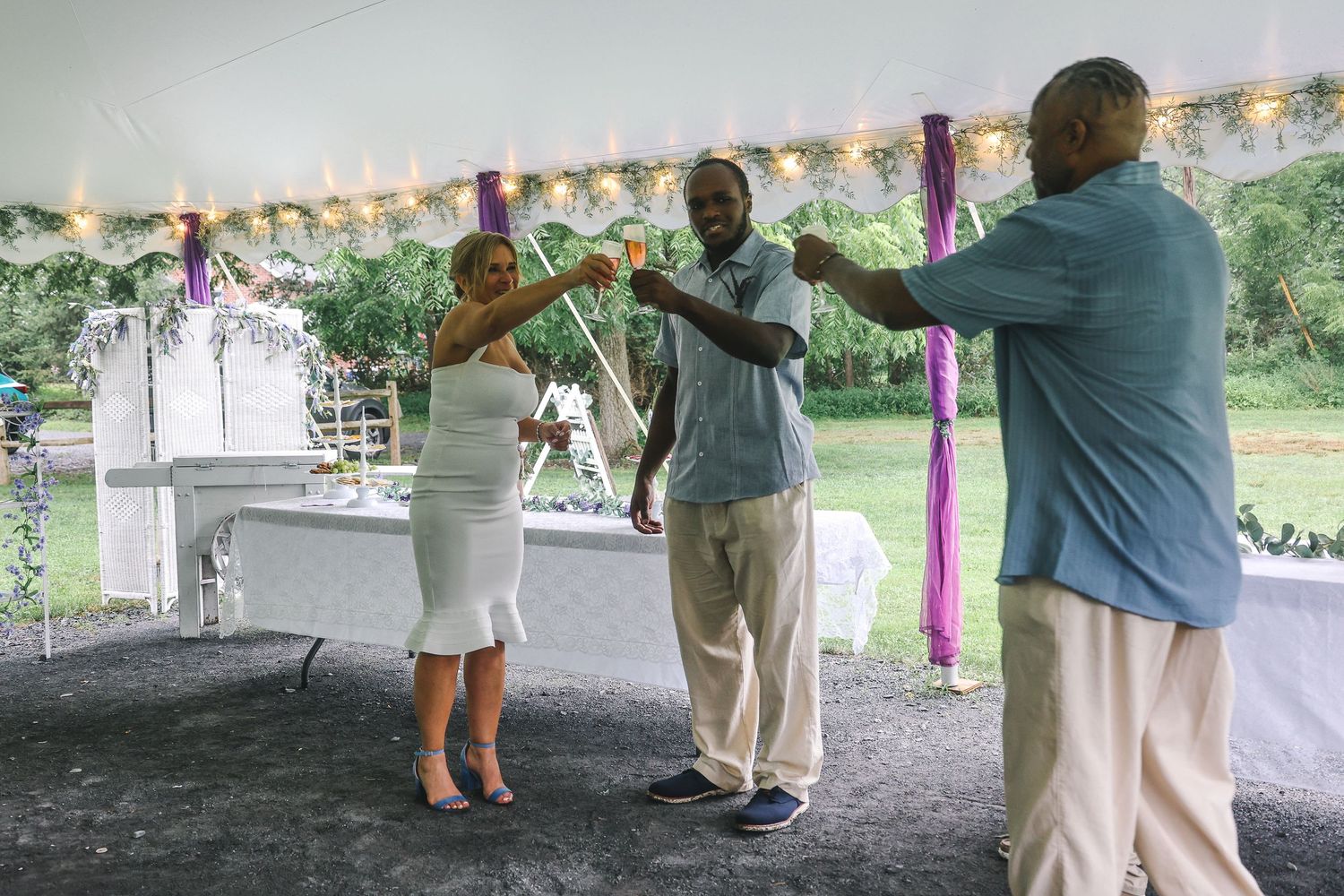 People dancing together under a white tent at an outdoor celebration with party decorations visible.