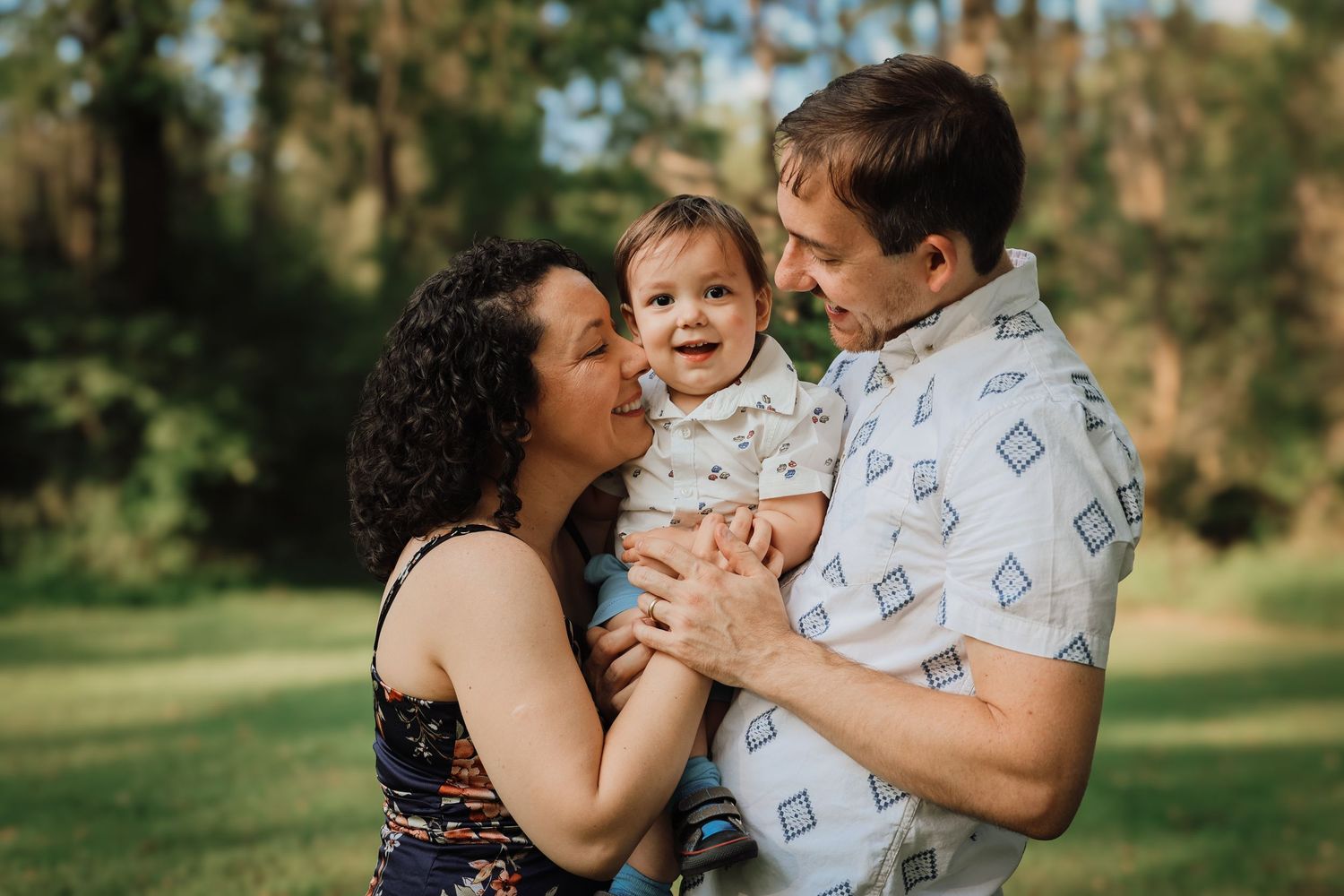 A loving family shares tender moments together in a sunlit outdoor setting during a photo session.
