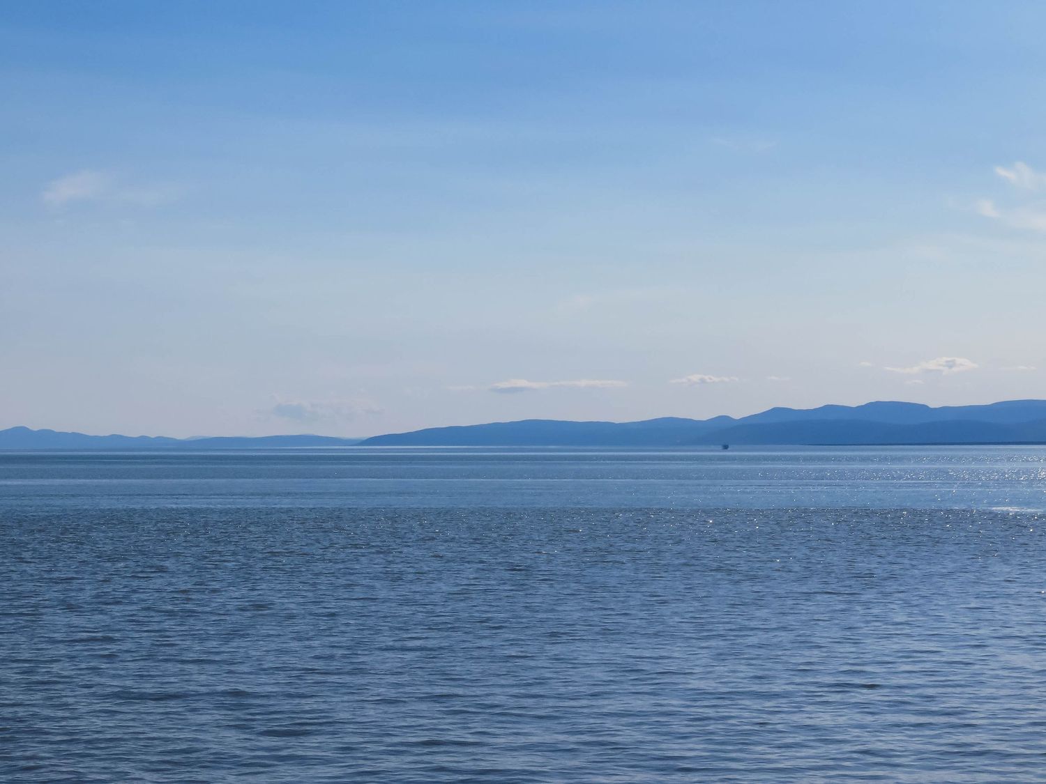 Serene lake view with layered mountain ranges creating a misty blue horizon.