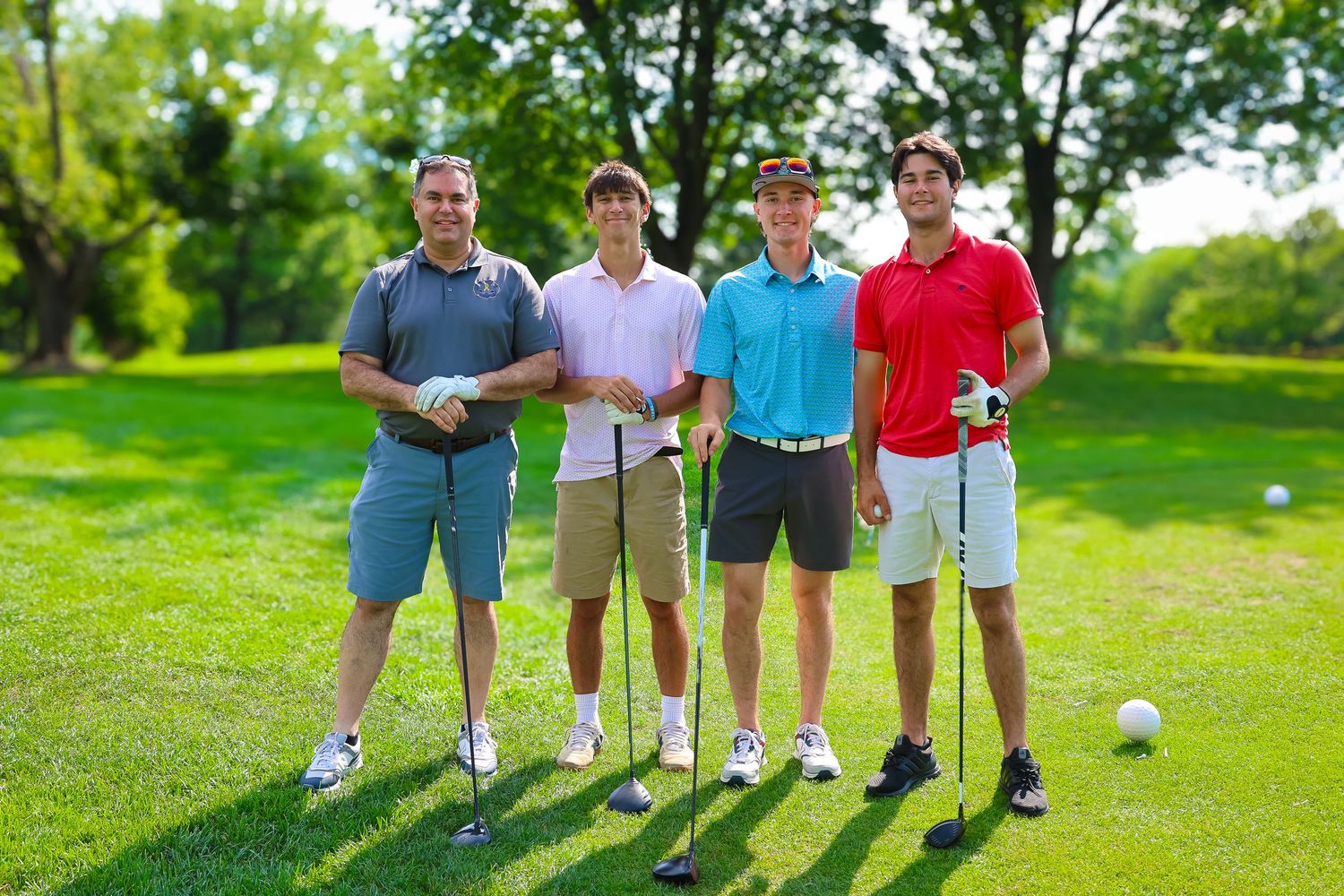 Group of golfers walking together on a lush green golf course during a sunny day.