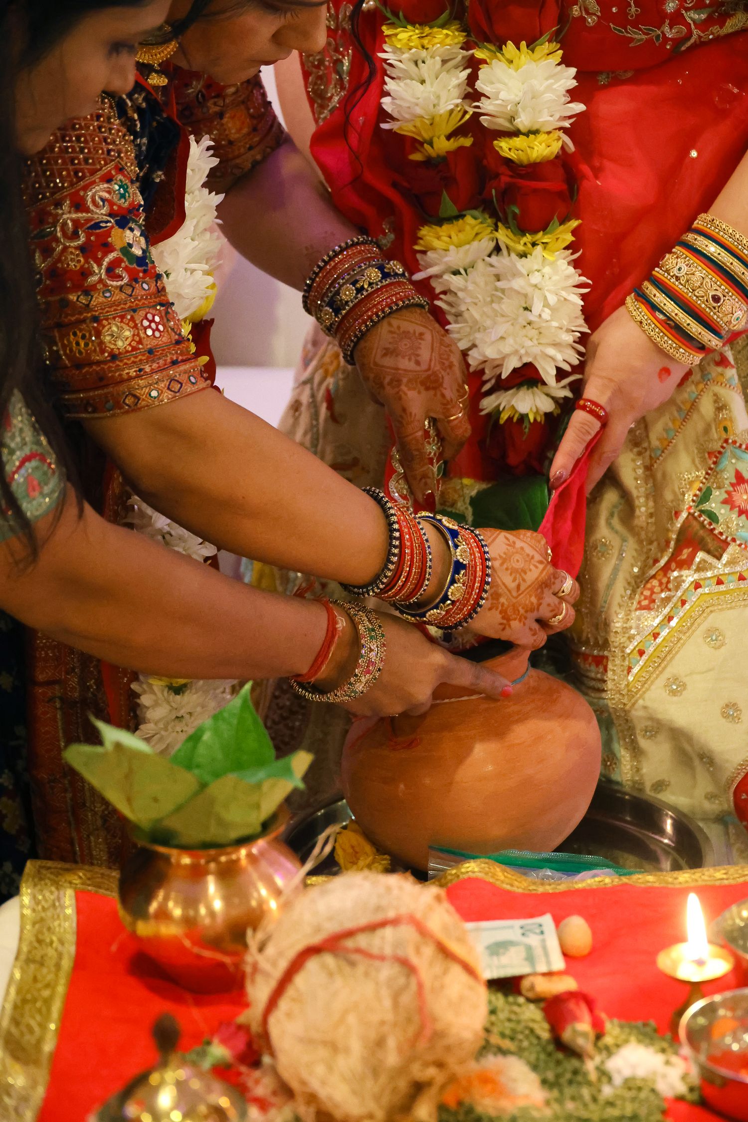Close-up view of hands adorned with traditional Indian wedding bangles and jewelry during a Hindu ceremony ritual.