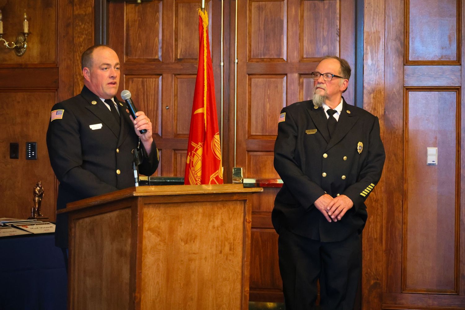 Police officers and officials stand in a wood-paneled courtroom during a formal legal proceeding.