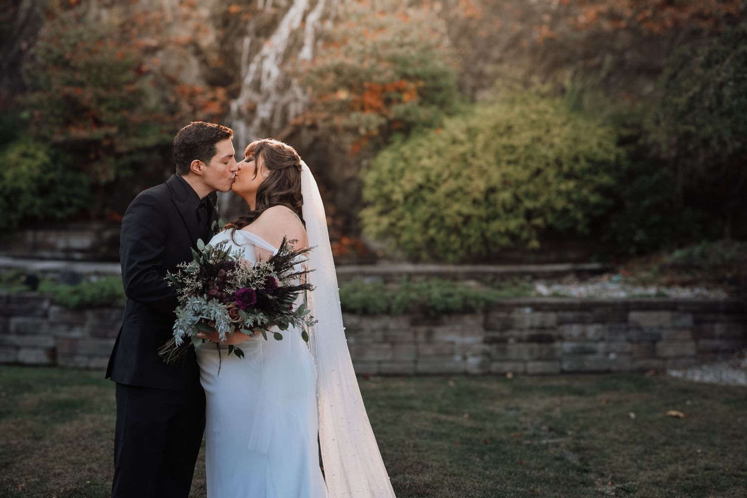 Wedding couple poses for intimate portraits in a natural outdoor setting with stone walls.