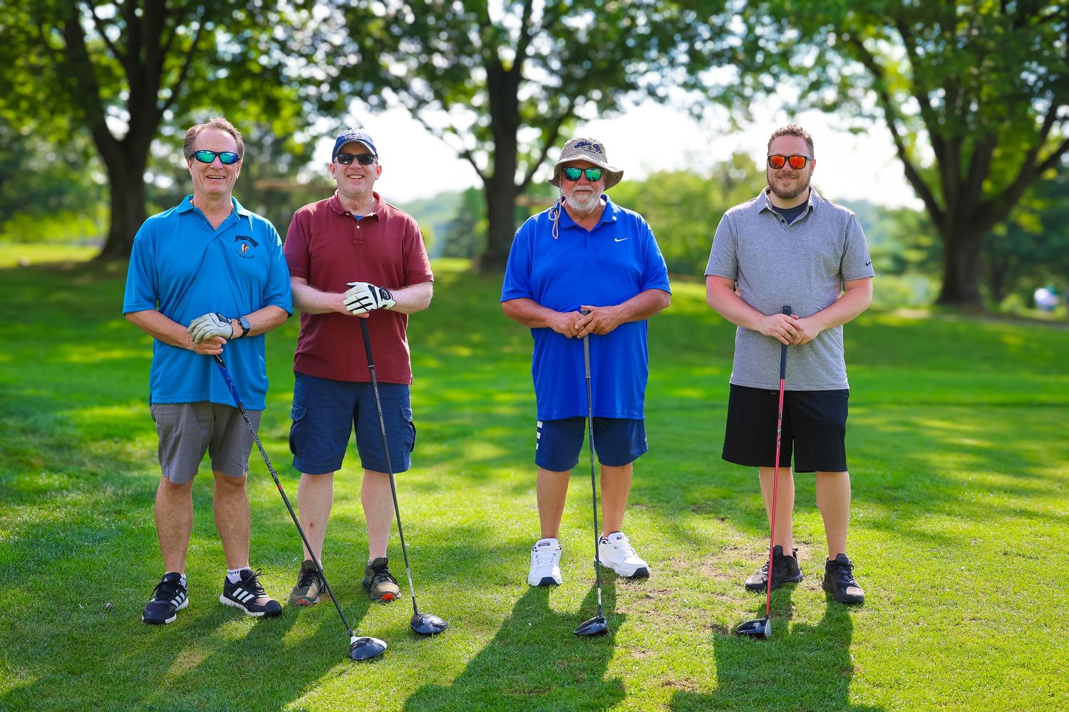 Two golfers in casual attire stand together on a lush green golf course fairway during a sunny day.
