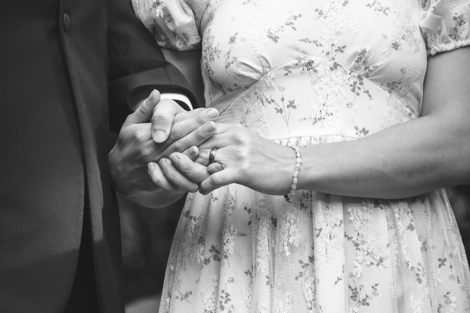 Black and white photo series showing close-up details of hands holding a delicate lace wedding dress.