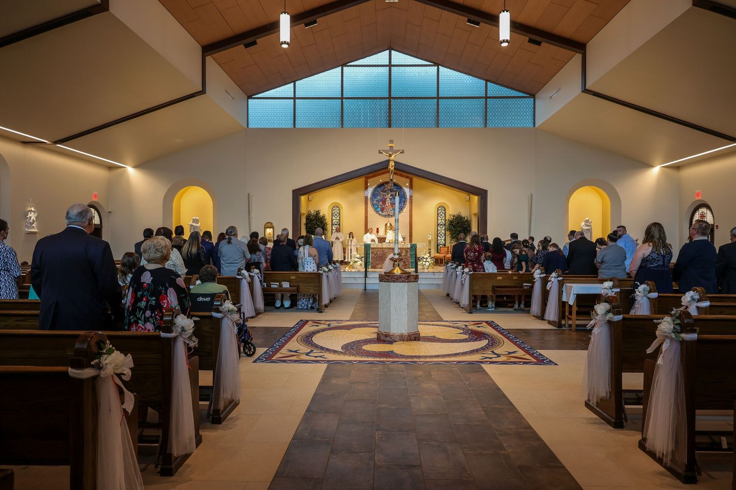 Interior panoramic view of a modern church sanctuary with wooden pews and large windows letting in natural light.