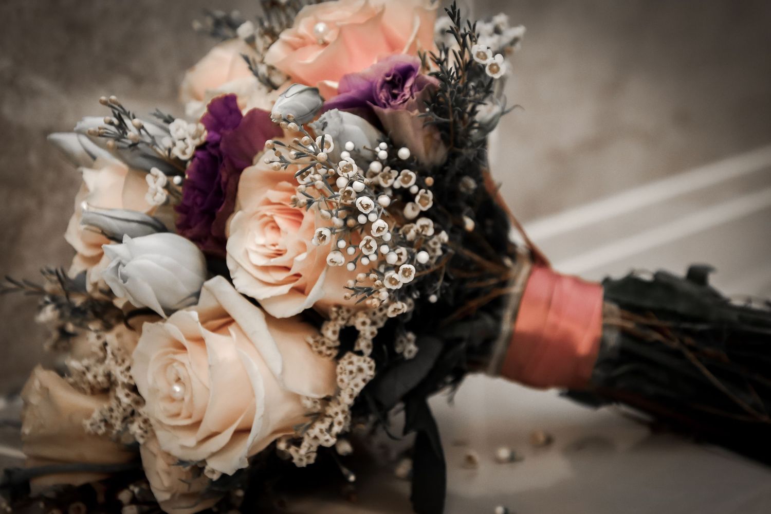 Close-up details of wedding bouquets with peach roses and baby's breath flowers arranged in vintage style.