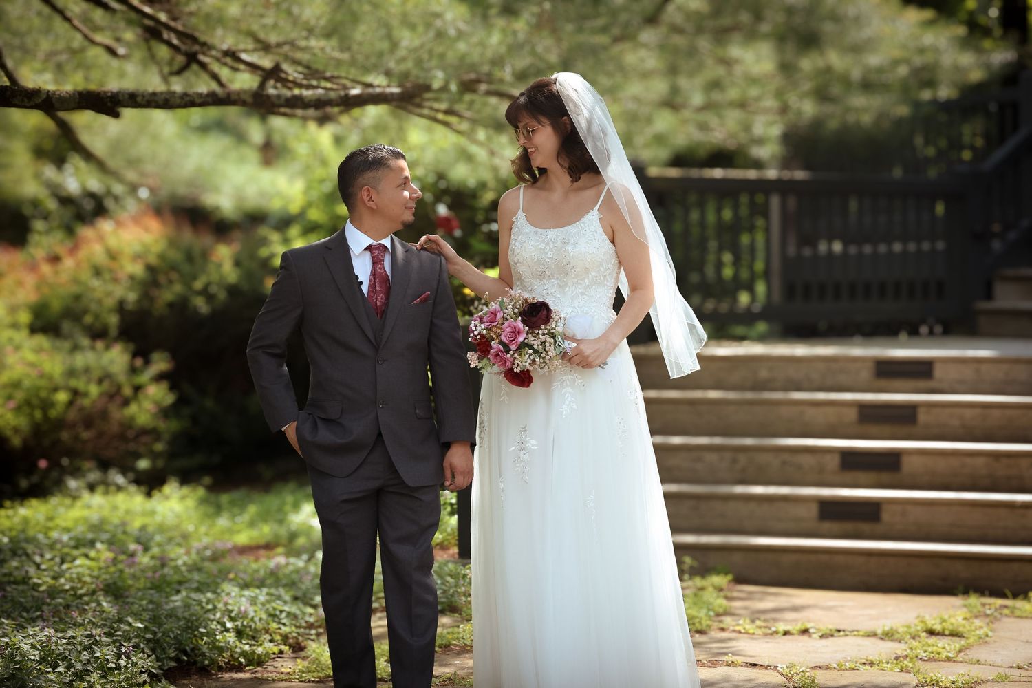 A couple in formal wedding attire walks together through a scenic garden path during their special day.