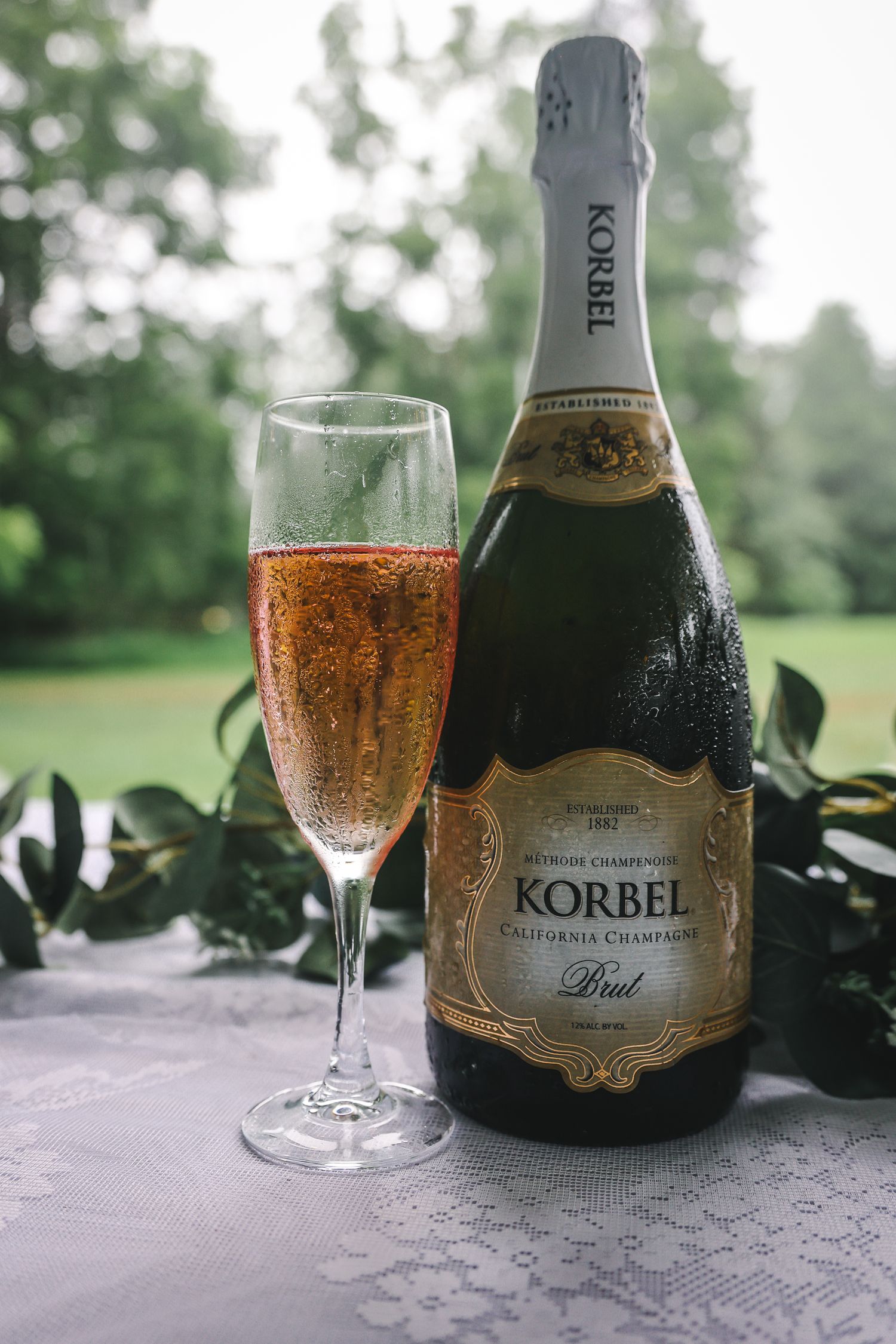 Three identical photos of a champagne flute filled with sparkling wine next to a Korbel bottle on a white tablecloth.