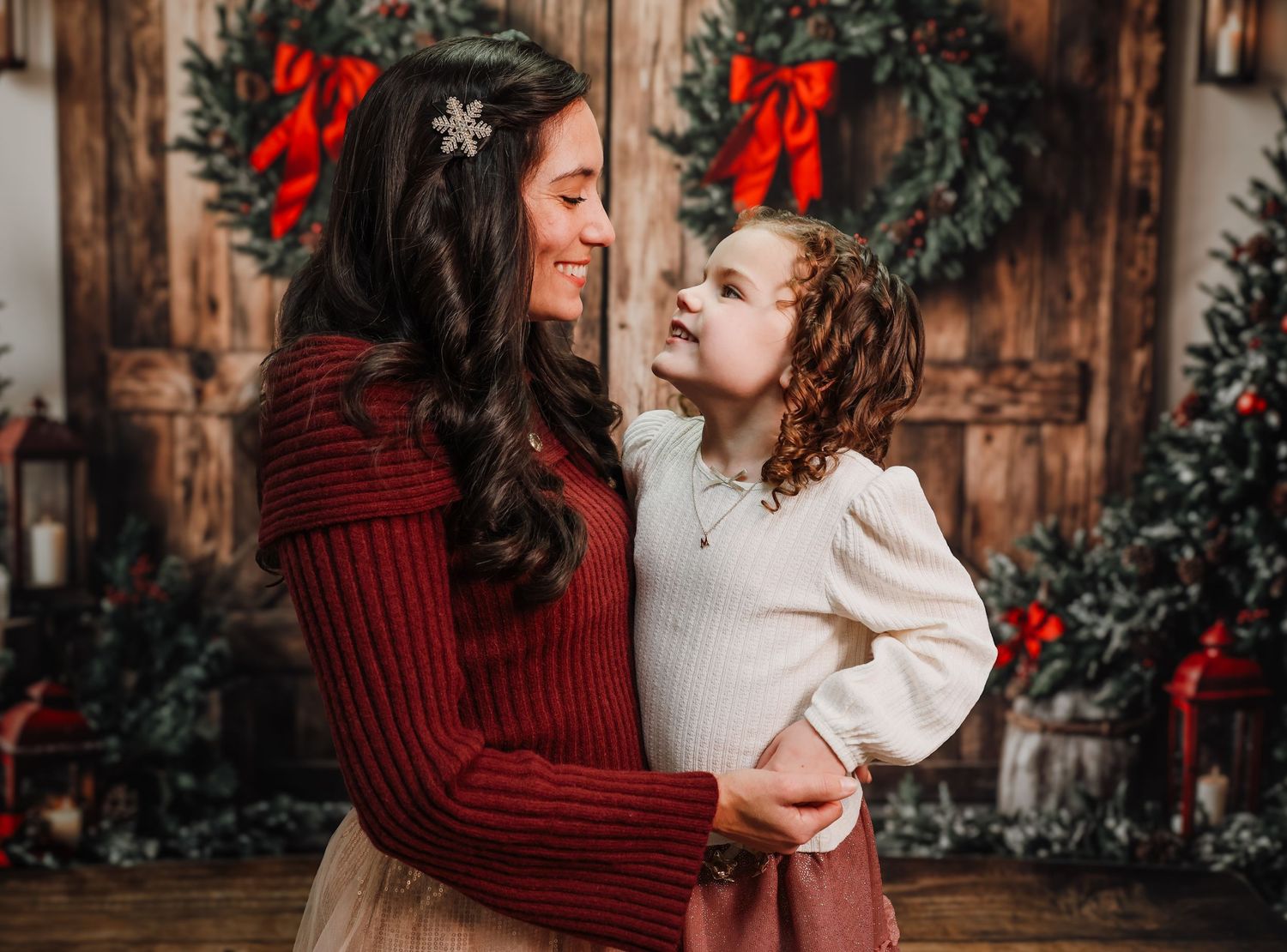 A festive holiday portrait of two people in cozy sweaters sharing a joyful moment in front of Christmas decorations.