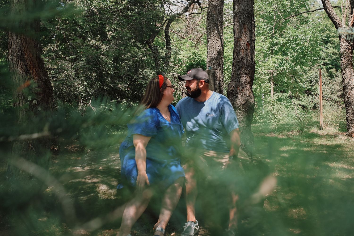 A couple enjoys a romantic stroll through a lush green forest path on a sunny summer day.