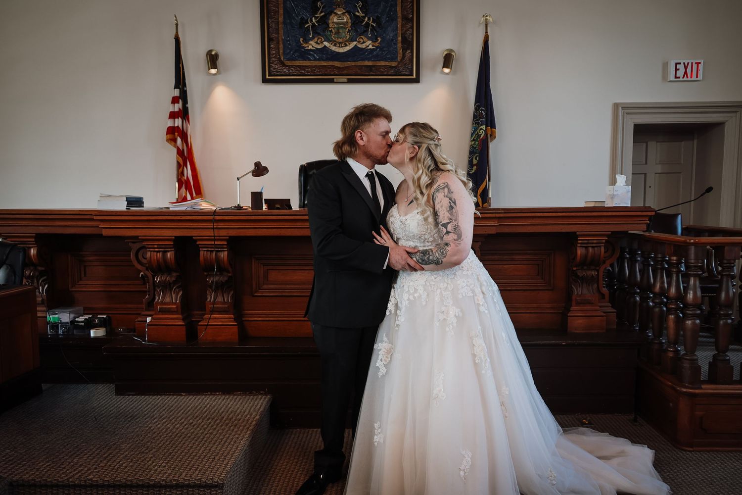Bride and groom share a kiss in a courthouse wedding ceremony, bride wearing a white ballgown with lace details.