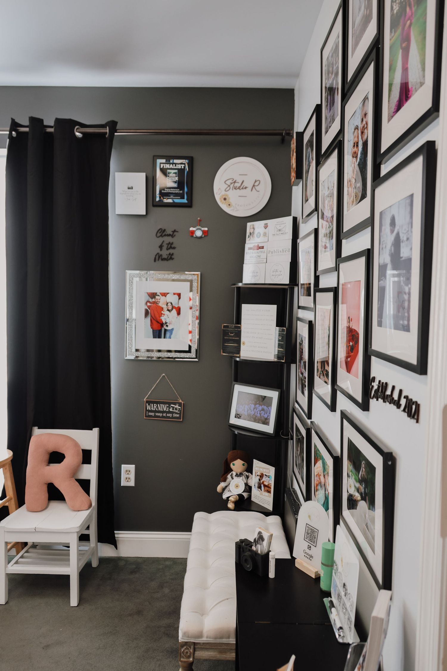 Art gallery hallway with dark walls features framed artwork and prints displayed in a clean, modern layout.