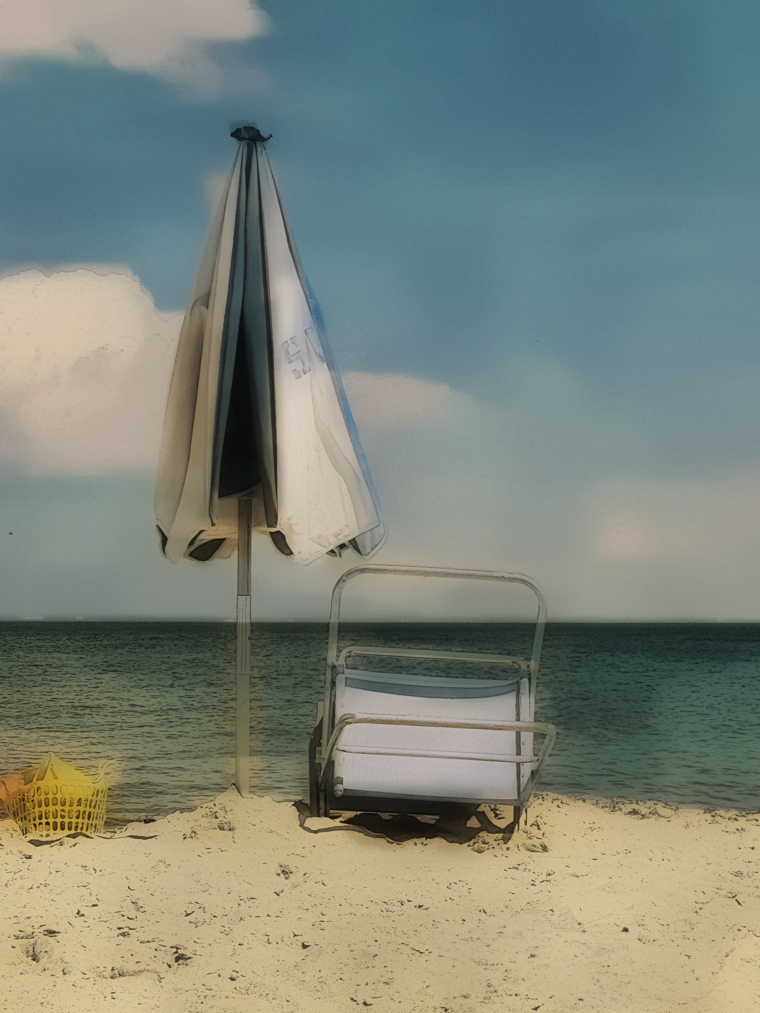 A folded beach umbrella and lounge chair on sandy shore with calm turquoise sea and blue sky backdrop.