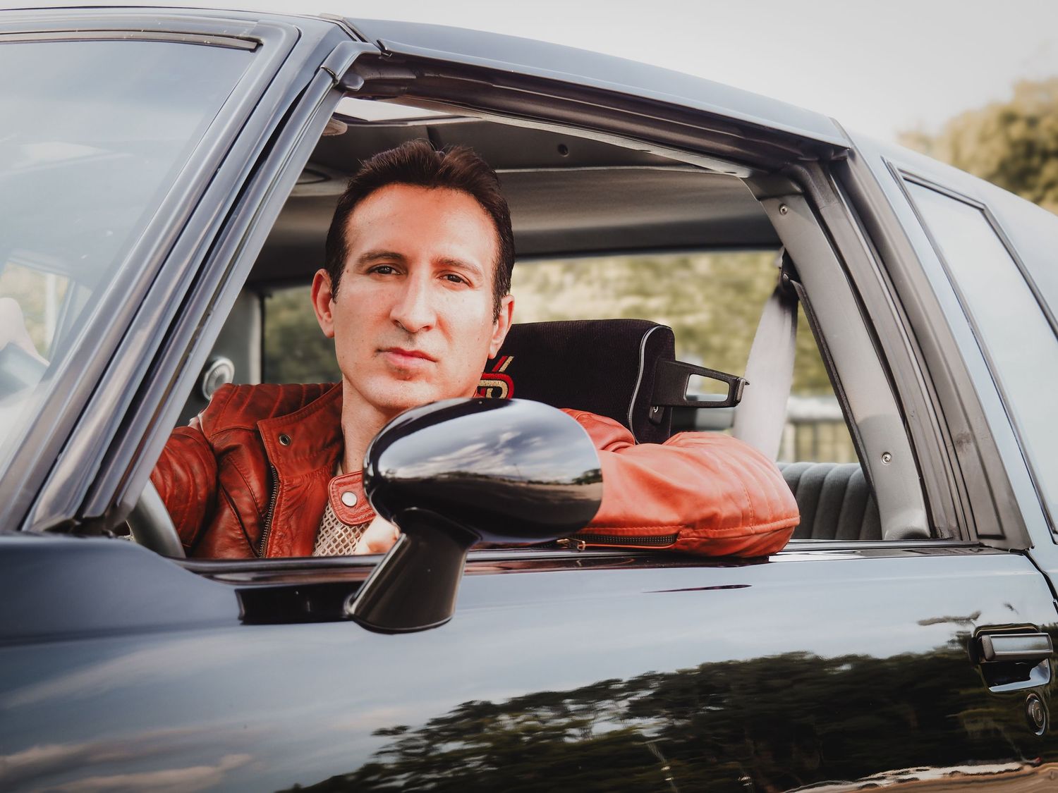A series of five similar photos showing someone sitting in the driver's seat of a black car.