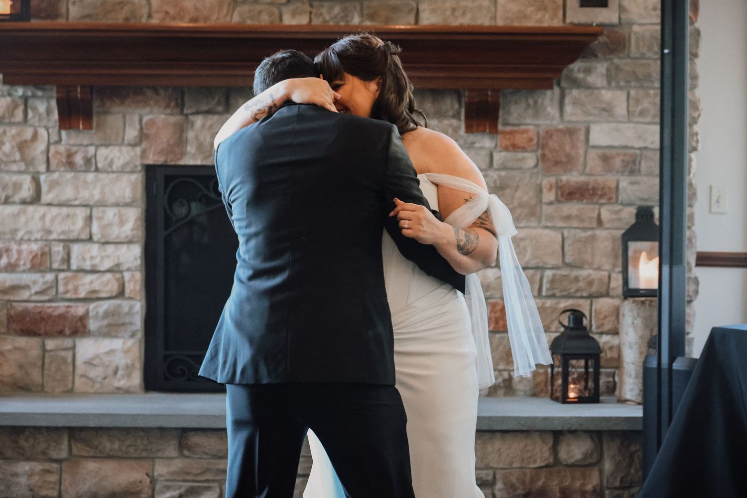 A couple shares an intimate moment at their wedding reception against a rustic stone wall backdrop.
